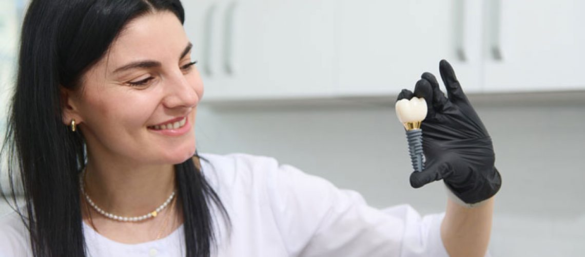 young woman holding dental implant mockup, artificial tooth roots into jaw canal. dental treatment concept.